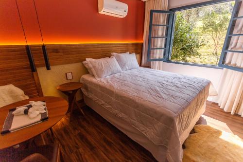 a bedroom with a bed and a table and a window at Umani Pousada in Bento Gonçalves
