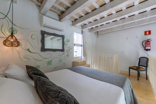 a bedroom with a white bed and a chair at La Casa de la Favorita in Tarifa