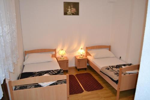 two beds in a small room with two lamps at Pansion Blažević in Međugorje