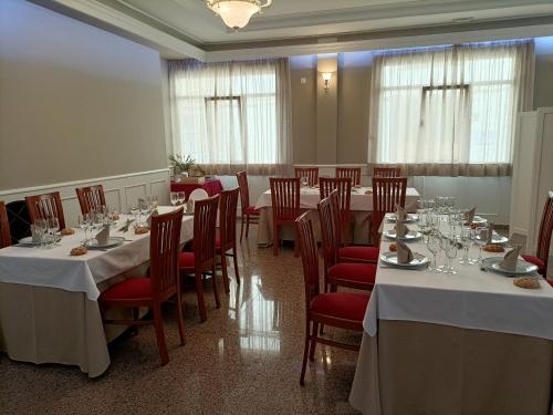 une salle à manger avec des tables blanches et des chaises rouges dans l'établissement Hotel Español, à La Pueblanueva