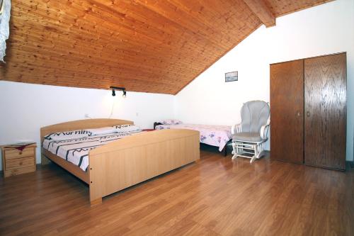 a bedroom with a bed and a wooden ceiling at APARTMANI JADRANKA s pogledom na more in Tisno