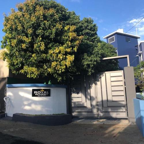 a tree in front of a house with a fence at Royal residency in Tindummal