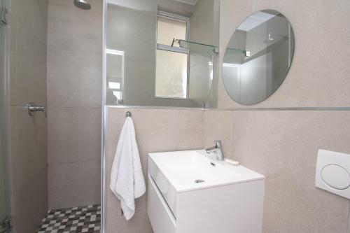 72 Sea Lodge Umhlanga Rocks في ديربان: حمام مع حوض أبيض ومرآة