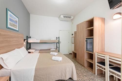 um pequeno quarto com duas camas e uma televisão em Hotel Admiral em Cesenatico