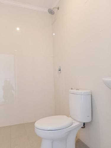 a white bathroom with a toilet and a shower at Karta House in Ubud