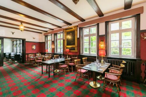 a dining room with tables and chairs and windows at Hotel Waldesruh Am See in Aumühle