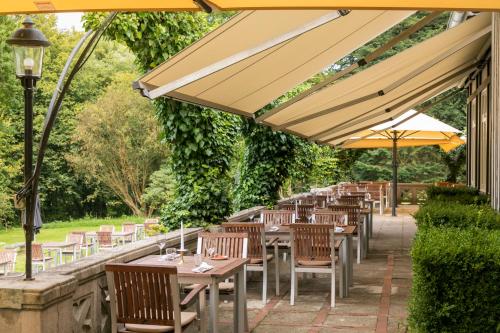 a row of tables and chairs under an umbrella at Hotel Waldesruh Am See in Aumühle