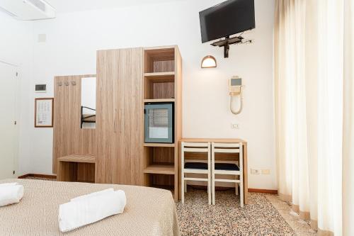 a bedroom with two beds and a tv on the wall at Hotel Admiral in Cesenatico