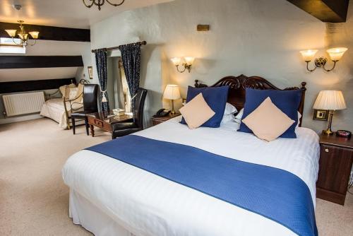 a bedroom with a large bed with blue and white pillows at The Old Bell Inn in Oldham