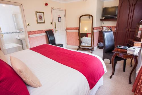 a bedroom with a red and white bed and a bathroom at The Old Bell Inn in Oldham