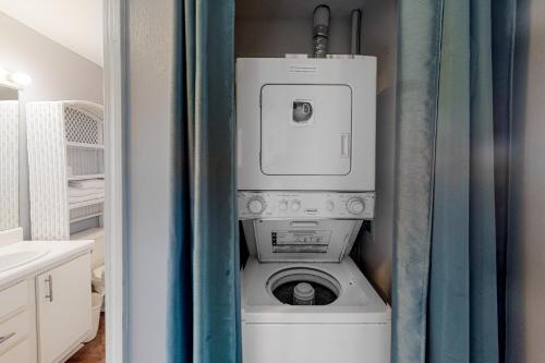 a washer and dryer in a bathroom with a curtain at Grand Beach Resort in Gulf Shores