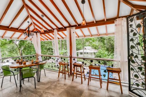 a dining room with a table and chairs and windows at Lost Pools Bungalow in Uvita