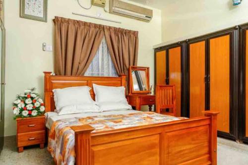 um quarto com uma cama de madeira e uma janela em Posh 7 BHK at BELLJEM Homes in Thrissur city em Thrissur