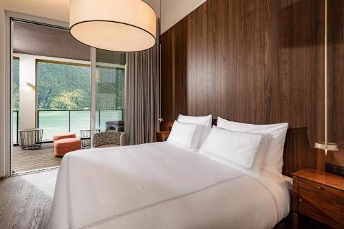 een slaapkamer met een groot wit bed en een groot raam bij ARIA Retreat & SPA - The Leading Hotels of the World, located within Parco San Marco Resort in Porlezza