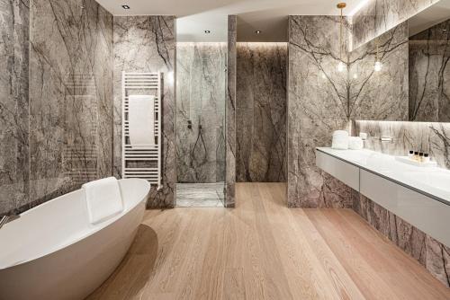 uma casa de banho com uma banheira, 2 lavatórios e um chuveiro em ARIA Retreat & SPA - The Leading Hotels of the World, located within Parco San Marco Resort em Porlezza