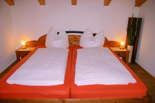 an orange bed with two white pillows on it at Ferienwohnung Schmid Ursula in Kiefersfelden