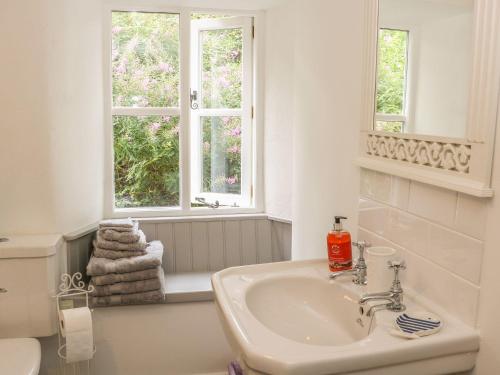 un bagno bianco con lavandino e due finestre di 2 Farfield Row a Sedbergh