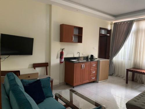 a living room with a couch and a kitchen at Avesta Hotel in Kampala