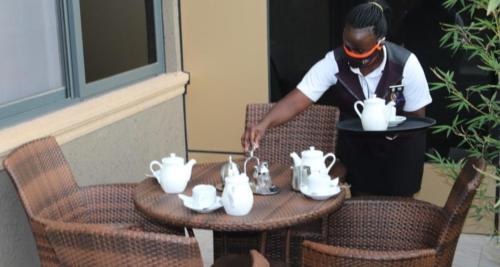 a woman standing in front of a table with tea pots at Avesta Hotel in Kampala