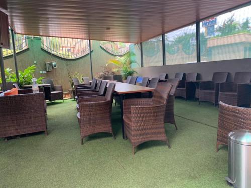 a dining room with a table and wicker chairs at Avesta Hotel in Kampala