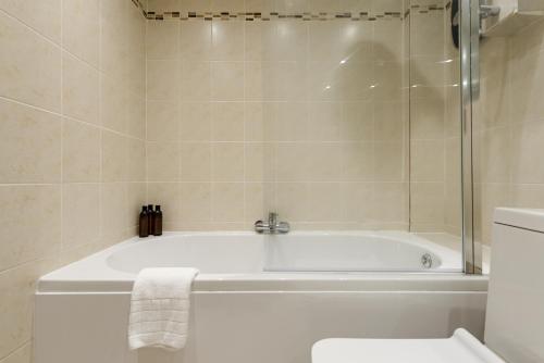a white bath tub in a bathroom with a toilet at The Old Town Cockburn Apartment in Edinburgh