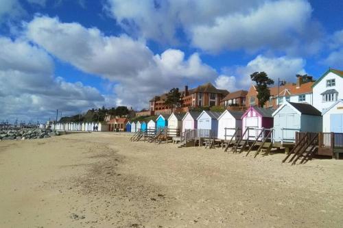 a row of colorful beach houses on the beach at 2 Bedroom Seafront Apartment in Felixstowe