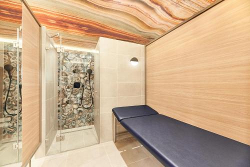 a walk in shower with a blue bench in a room at Hotel Europa Fit Hévíz in Hévíz