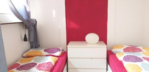a bedroom with two beds and a red wall at Aussicht in Hahnenklee-Bockswiese