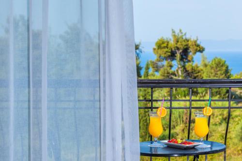 two glasses of orange juice on a table on a balcony at Hotel Kriopigi in Kriopigi