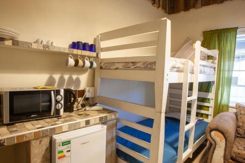 a bedroom with a bunk bed and a kitchen with a microwave at Strand Family studio en-suite 6 sleeper Kitchenette Helderberg CT in Cape Town