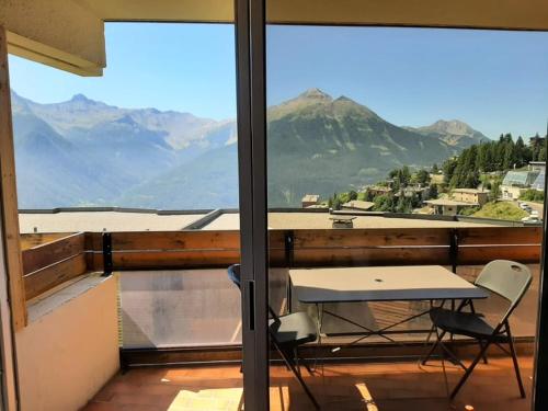 a table and chairs on a balcony with a view of mountains at LE COSY aux pieds des pistes appartement avec balcon PLEIN CENTRE in Orcières