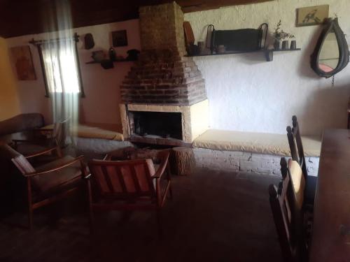 sala de estar con chimenea, sillas y sofá en La Carmencita casa de campo, Manzanares, Pilar en Pilar