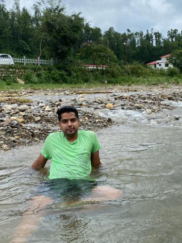a man standing in the water in a river at River Stay - Homestay by Wanderlust Rural Tourism in Dehradun