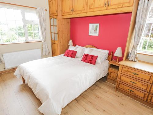 a bedroom with a white bed and a red wall at Clodagh's Cottage in Collooney