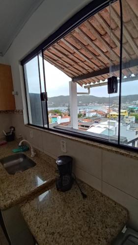 a kitchen with a large window with a view of a city at Pousada Mar Dos Anjos in Arraial do Cabo