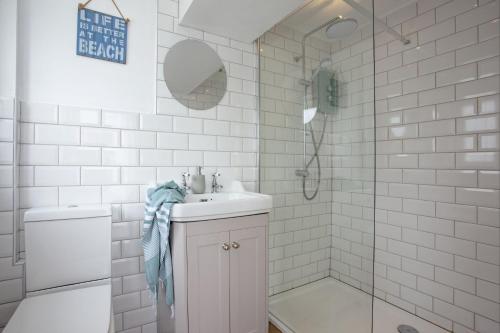 a white bathroom with a sink and a shower at Birdcage Cottage, Kingsand in Kingsand
