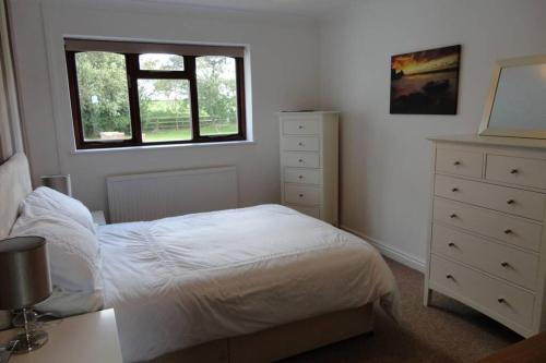 a bedroom with a bed and a dresser and a window at Birchwood Cottage with hot tub in Valley