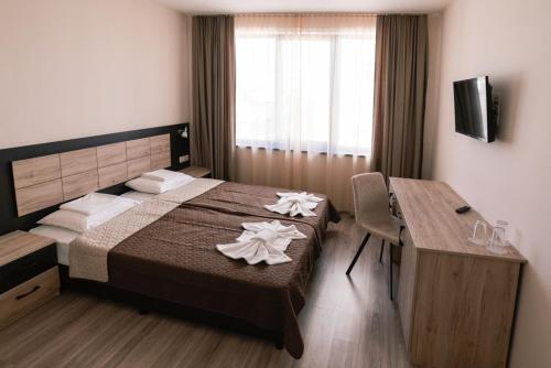 a bedroom with a bed and a desk and a television at Hotel Terra in Gorna Oryakhovitsa