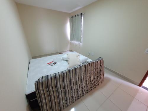 a small bed in a room with a window at Casa Duplex Nova em Iriri in Iriri