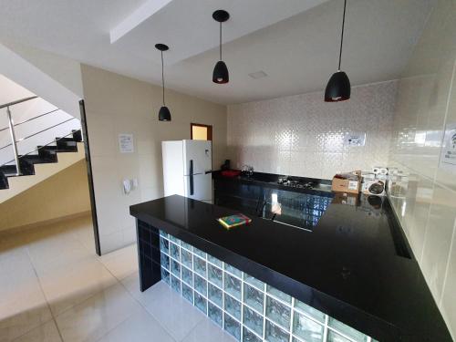 a kitchen with a black counter and a refrigerator at Casa Duplex Nova em Iriri in Iriri