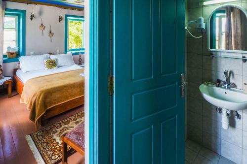 a room with a bed and a sink and a door at Vikos Hotel in Monodendri