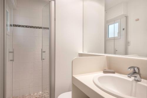 une salle de bain blanche avec un lavabo et une douche dans l'établissement À 260m de la plage, bel appartement pour 4, à La Baule