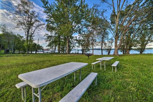 a picnic table and two benches in a park at Charming Lakefront Home with Grill and Fire Pit! in New Concord