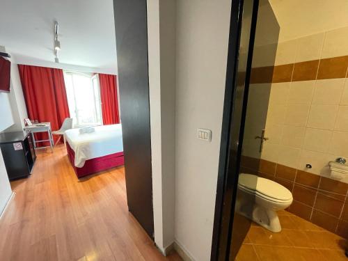 a bathroom with a toilet and a room with a bed at Hostel Pipištrelo in Pula