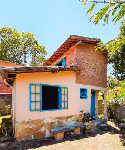 a small house with blue windows and a brick at Chalé da Léia in Conceição da Ibitipoca