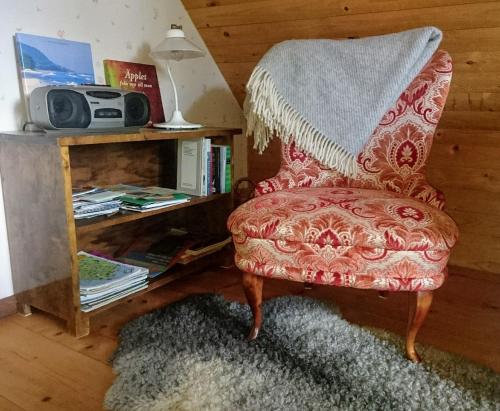 a living room with a red chair and a book shelf at Brösarp Källagården Vindsvåning 2 rum och kök in Brösarp