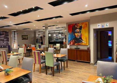 a restaurant with tables and chairs and a painting of a woman at Hotel Colonial Tafi del Valle by DOT Tradition in Tafí del Valle