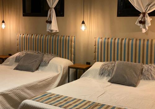 two beds in a hotel room with two at Hotel Colonial Tafi del Valle by DOT Tradition in Tafí del Valle