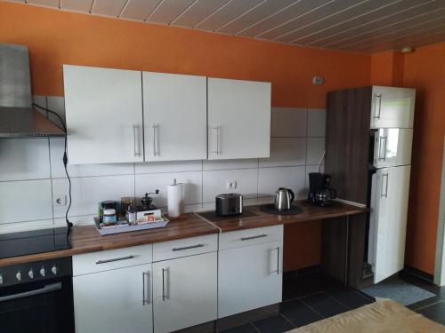 a kitchen with white cabinets and a white refrigerator at Joys Ferienwohnung in Oberhausen
