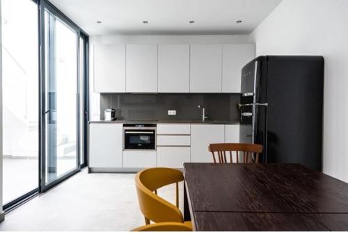 a kitchen with a table and a black refrigerator at Casa dos Retratos Faro in Faro